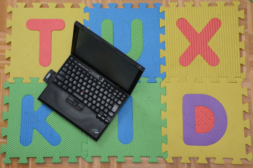 Photo of old IBM laptop on mat that reads TUX KID